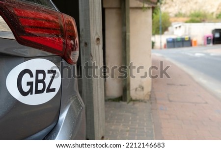 Close up of GBZ sticker on rear of a dark grey car, parked in driveway of building. The letters represent the International Vehicle Registration Code for the British Overseas Territory of Gibraltar.