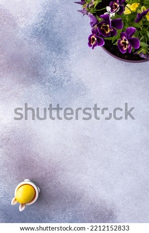 Colorful Easter eggs and cute bunnies on a pastel pink background, pansies in a pot, top view, copy space