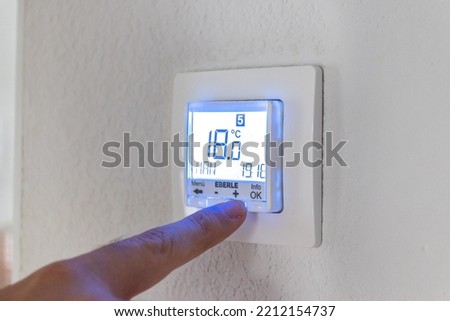 man adjusting the temperature thermostat by hand Royalty-Free Stock Photo #2212154737
