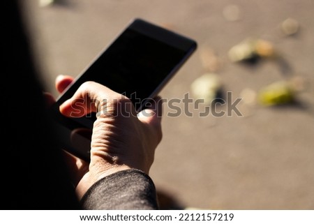 Close-up of an unrecognizable woman using smart phone outdoors