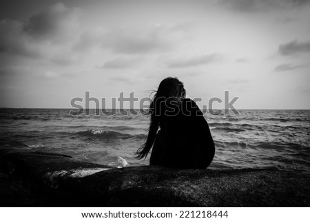 Young women siting alone on a rock at the beach,Sad concept Royalty-Free Stock Photo #221218444