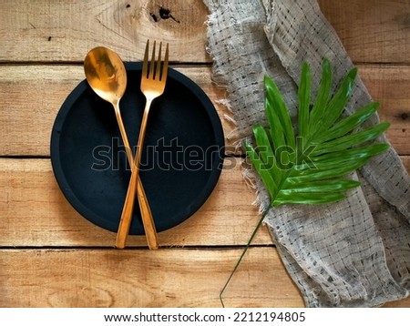 Fork and spoon on black disc at wood background 
