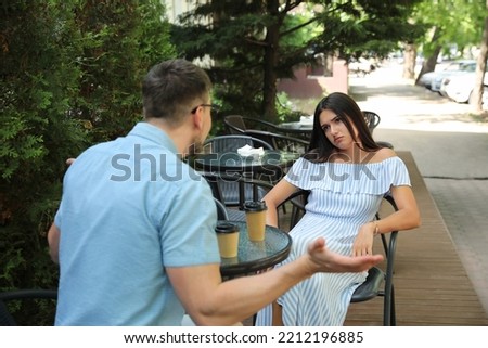Young woman getting bored during date with man at outdoor cafe Royalty-Free Stock Photo #2212196885