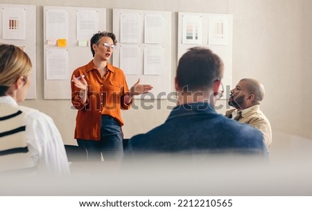 Mature businesswoman pitching her idea to her team during a meeting. Mature team leader discussing her strategy with her colleagues. Group of businesspeople working together in a creative office. Royalty-Free Stock Photo #2212210565
