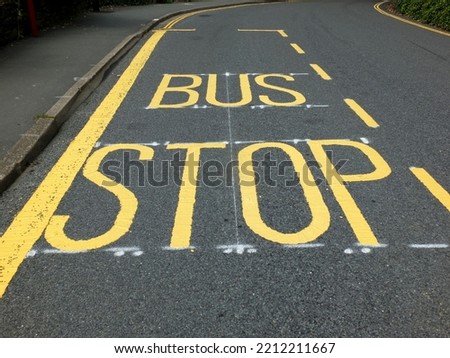 newly painted yellow bus stop road sign and markers on a black tarmac narrow rural road