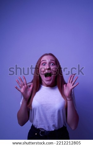 Frightened caucasian female teenage with open mouth looking at camera. Girl of zoomer generation. Modern youngster lifestyle. Isolated on blue with white light background. Studio shoot. Copy space