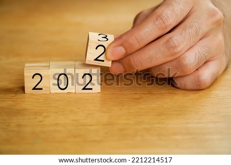 Beginning and start of the new year 2023. Preparation for happy new year ,new life, new business, plan, goals, strategy concept. Hand flips wooden cubes with 2022 to 2023 on smart background.