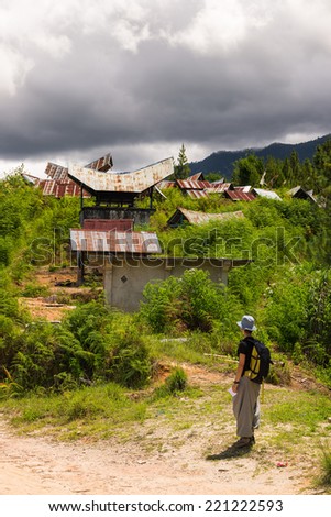 Hiker looking at traditional cemetery with tipical boat shaped roofs, named Tedong Tedong, in Mamasa region, South Sulawesi, Indonesia.