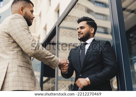Business people outdoor meeting. Two men in suits hold out their hands to each other. A handshake is a mutual agreement. Greeting and interpersonal contact