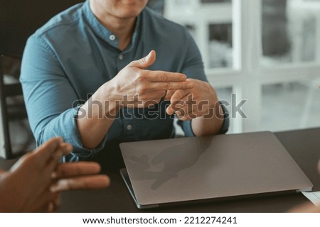 Close up of businessman using sign language while talking with client sitting in office