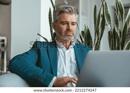 Busy Mature businessman workingon laptop while sitting in modern coworking Royalty-Free Stock Photo #2212274247