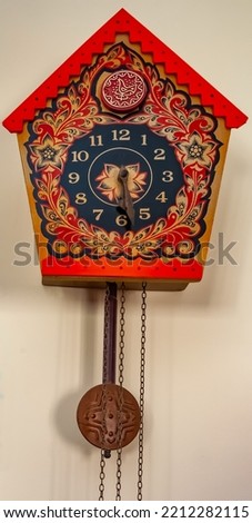 Mechanical clock with a cuckoo and a pendulum close-up on the background of the apartment wall
