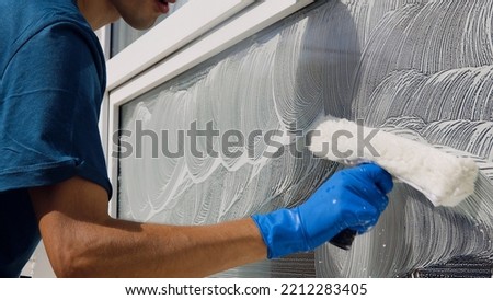Male professional cleaning service worker in overalls cleans the windows and shop windows of a store with special equipment Royalty-Free Stock Photo #2212283405