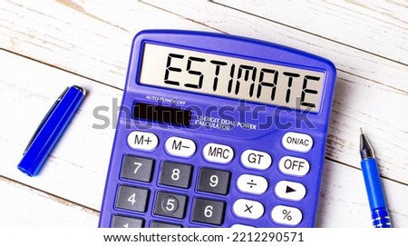 Flat lay or top view of blue pen and calculator with ESTIMATE text on light wooden table.