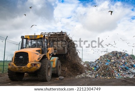bulldozer working on landfill with birds in the sky Royalty-Free Stock Photo #2212304749
