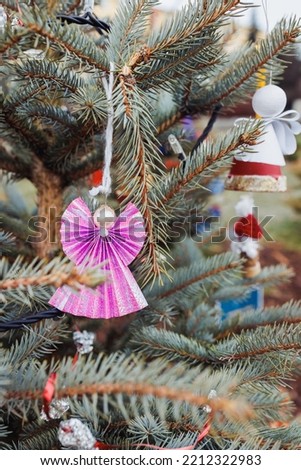 Handmade angel decoration of paper and pearl bead on Christmas tree outdoor. Diy creative ideas for children. Environment, recycle and zero waste concept. Selective focus, copy space