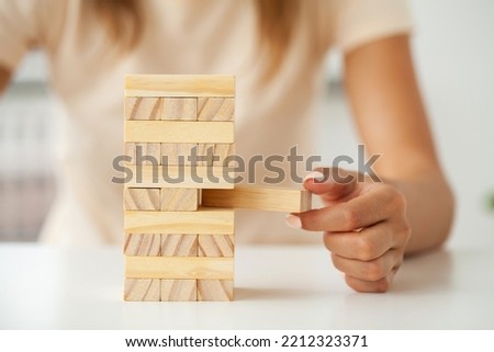 Hand of a young business woman to play wood block game with strategy and business systematic project management