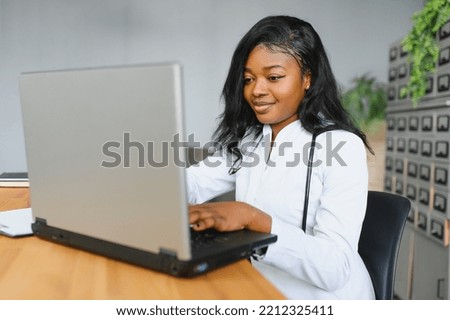 healthcare, medical and technology concept - african female doctor with laptop. Royalty-Free Stock Photo #2212325411