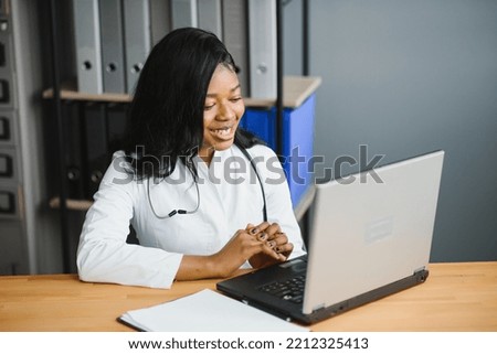healthcare, medical and technology concept - african female doctor with laptop. Royalty-Free Stock Photo #2212325413