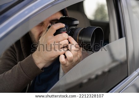 Investigator or private detective, reporter or paparazzi sitting in car and taking photo with professional camera, close up Royalty-Free Stock Photo #2212328107