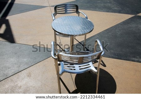 Chair. Patio Furniture. Aluminum Chair and Table on a Patio. Restaurant Chair. Outdoor seating. Metal Furniture for relaxing and dining. Outside Cafe Chair and Table for Eating and Relaxing. 