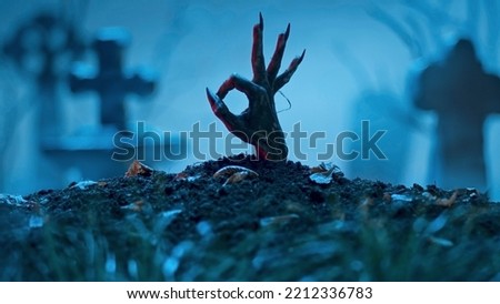 Zombie hand makes okay gesture out of grave. Holiday event halloween concept