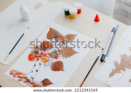 DIY picture on desk made from dry birch leaves. Autumn activities for children