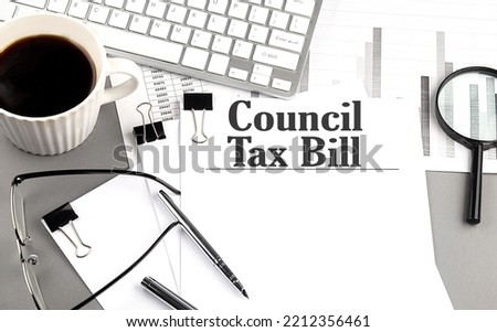 COUNCIL TAX BILL text on a paper with magnifier, coffee and keyboard on a grey background