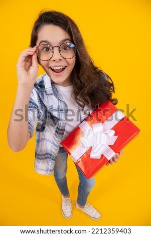 studio shot of surprised teen girl hold present. teen girl holding box of present. teen girl