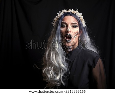 Woman in Halloween costume on black background. Skeleton or skull makeup.