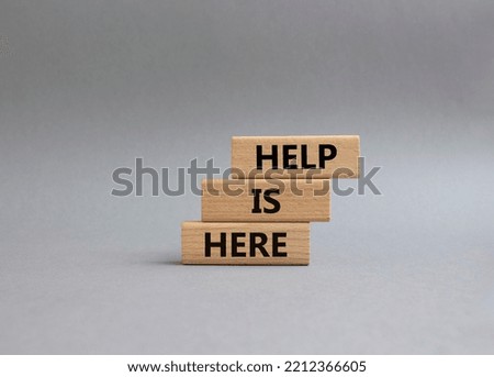 Help is here symbol. Wooden blocks with words Help is here. Beautiful grey background. Business and Help is here concept. Copy space.