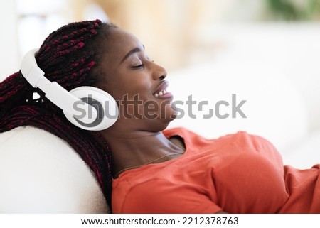 Smiling Relaxed Black Woman In Wireless Headphones Listening Music At Home, Closeup Shot Of Young African American Female Leaning Back On Couch With Closed Eyes, Enjoying Favorite Playlist, Side View