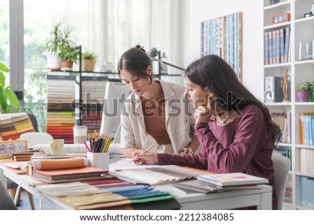 Young female interior designers and architects in the office, they are working together on a project and checking a house plan Royalty-Free Stock Photo #2212384085