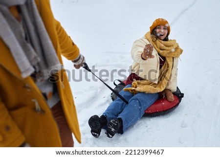 High angle view at young couple sledding downhill while enjoying fun winter activities together