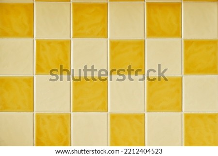 Original 1970s retro wall tiles. Square orange and yellow checkered tiles. Vintage style home decor. Colorful retro wall tiles with white grout Royalty-Free Stock Photo #2212404523