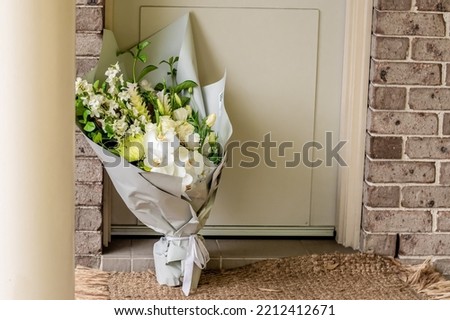 A bouquet of flowers delivered on a porch doorsteps of a house front door. Surprise contactless delivery. Mother's Day, Valentine's Day, Birthday, Anniversary and Celebration Royalty-Free Stock Photo #2212412671