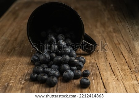 cup of blueberries on wood with dark background