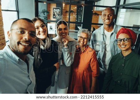 Happy business colleagues smiling at the camera while taking a staff selfie. Group of multicultural businesspeople running a successful startup in an inclusive workplace.