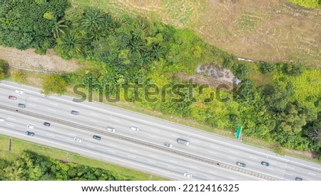 Aerial view directly above a six lane highway. Top view of asphalt road passes through the field and forest. Aerial. Sedan cars driving by the highway. Top view from drone. aerial photo autobahn road  Royalty-Free Stock Photo #2212416325