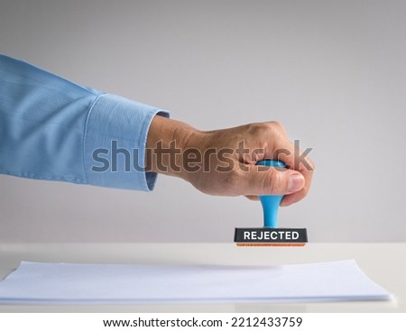 Rubber stamp, hand pressing on paper, with word Rejected. Royalty-Free Stock Photo #2212433759