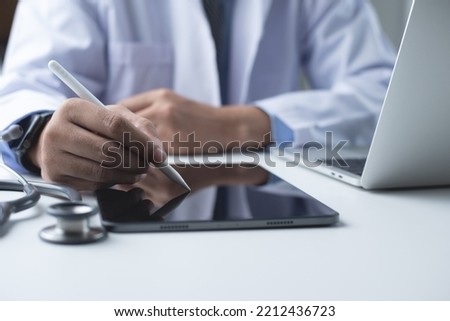 Doctor using stylus pen on digital tablet, filling medical checklist and prescription on digital document with laptop computer on table in medical office  in hospital, close up