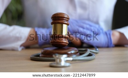 Close-up of female hands in gloves striking with judge hammer. Medical malpractice, personal injury lawyer and healthcare legal aspects concept