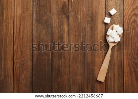 Spoon with sugar cubes on wooden table, top view. Space for text Royalty-Free Stock Photo #2212456667