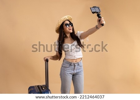 Young Asian tourist backpacker woman smiling and taking a selfie and blog isolated on beige background Royalty-Free Stock Photo #2212464037