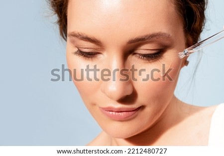 Beautiful real woman with jar of moisturizing oil serum and eyedropper. Natural organic cosmetics product for skincare and facial skin regeneration. Daily luxury beauty treatment. Royalty-Free Stock Photo #2212480727