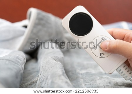 man operating a controller of an electric blanket horizontal composition Royalty-Free Stock Photo #2212506935