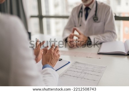 Closeup picture of female medical worker, discussing the symptoms with her mentor at the hospital.