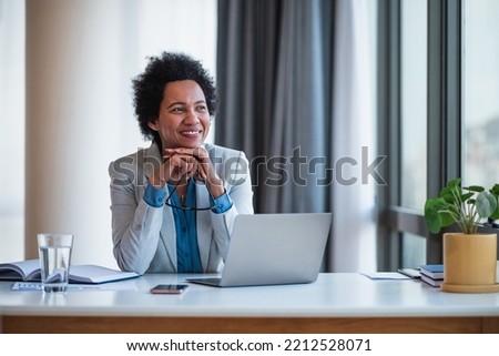 Joyful female african-american company manager in a suit, taking a breather, at the office.