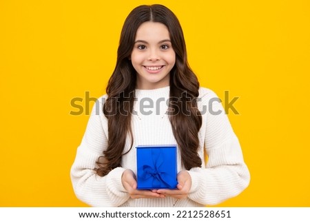 Child with gift present box on isolated studio background. Gifting for kids birthday. Excited teenager girl.