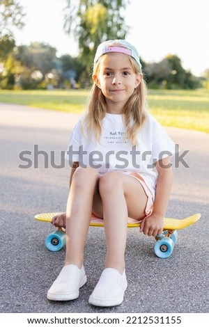 Child riding skateboard in summer park. Little girl learning to ride skate board. Active outdoor sport for school and kindergarten kids. Children skateboarding. Preschooler sitting on skateboard.
